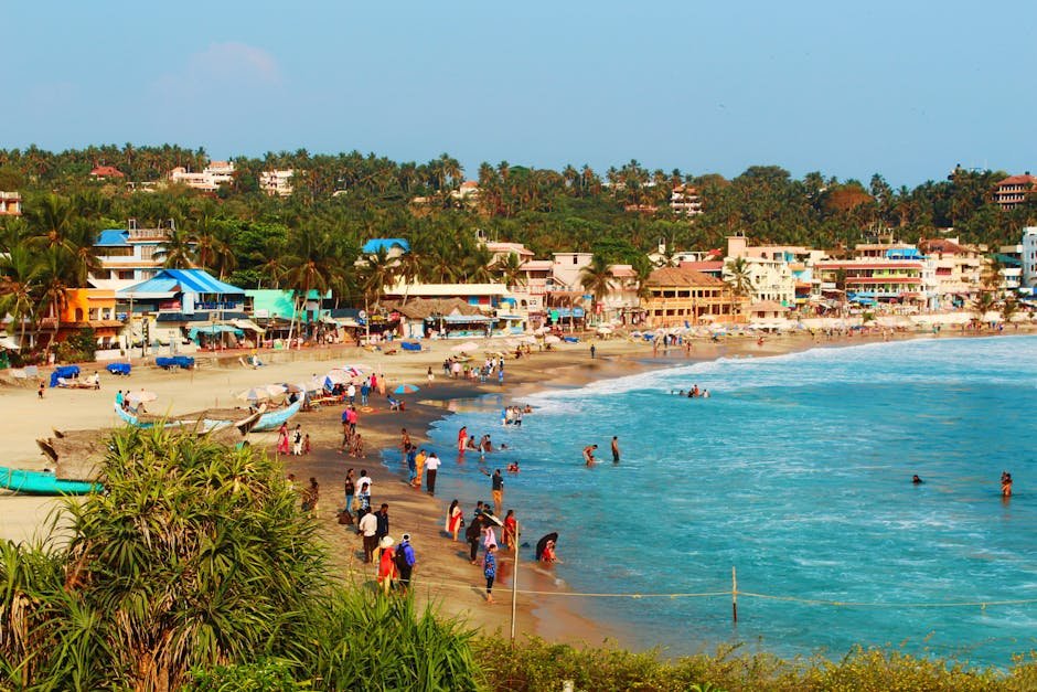 Beachfront village bustling with tourists, vibrant buildings, and palm trees on a sunny day.